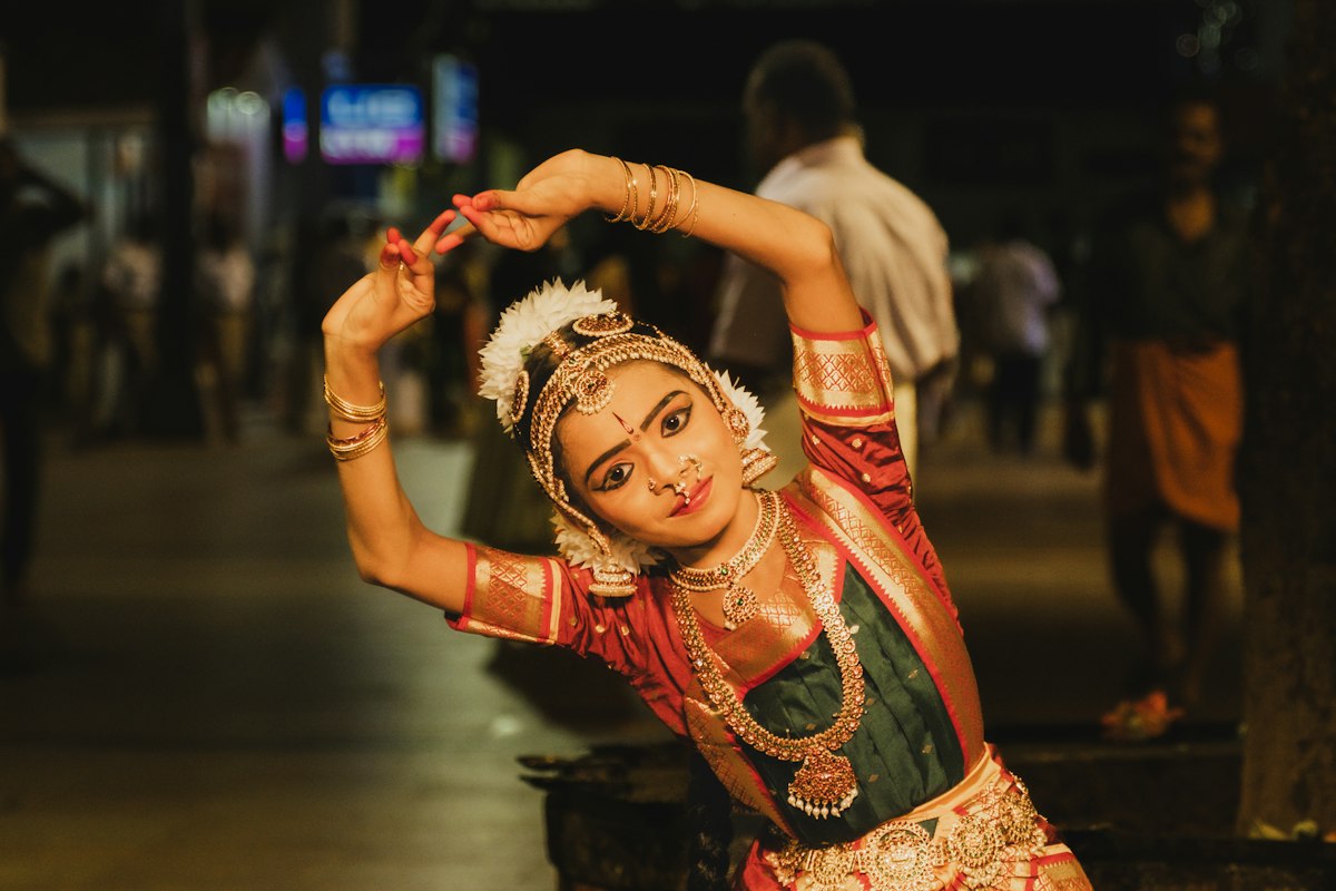 A young classical dancer mid-pose in full traditional costume and jewellery