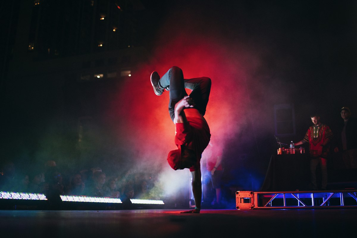 Break-dancer performing a freeze under coloured stage lights
