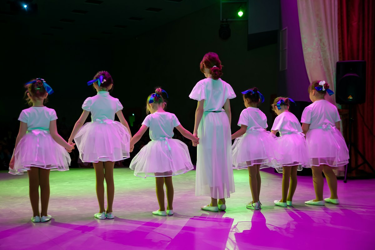 Young girls in white outfits dancing together on stage