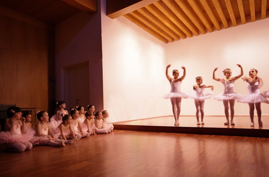 Little ballerinas in pink tutus rehearsing on stage